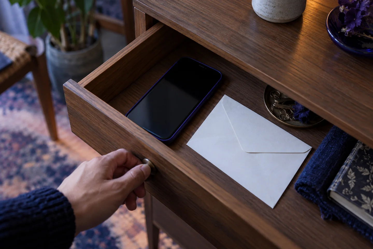 A phone and blank envelope beside a private desk drawer